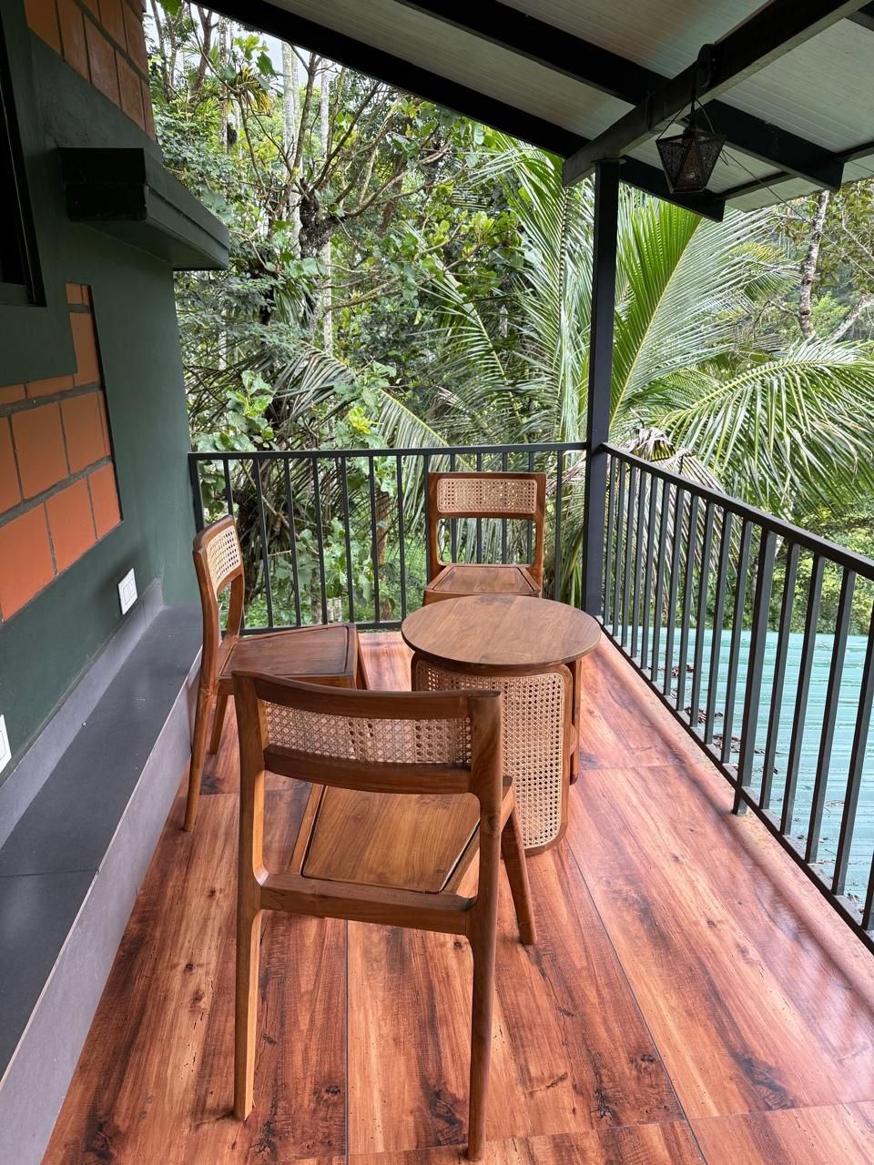 Balcony with cane chairs and a wooden floor looking into dense forest